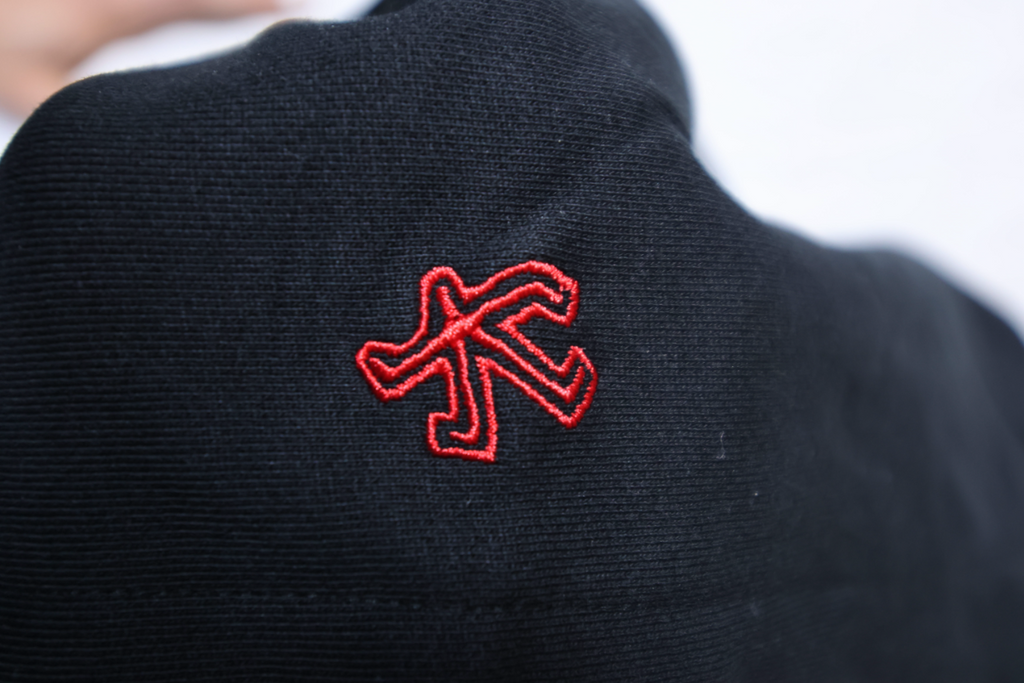 Black garment with a red embroidered logo on a blurred background